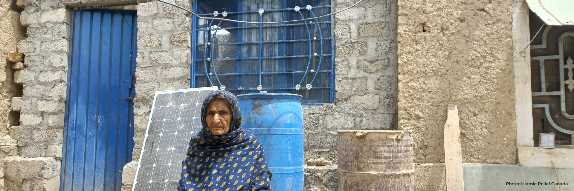 Woman in Pakistan next to her restored house