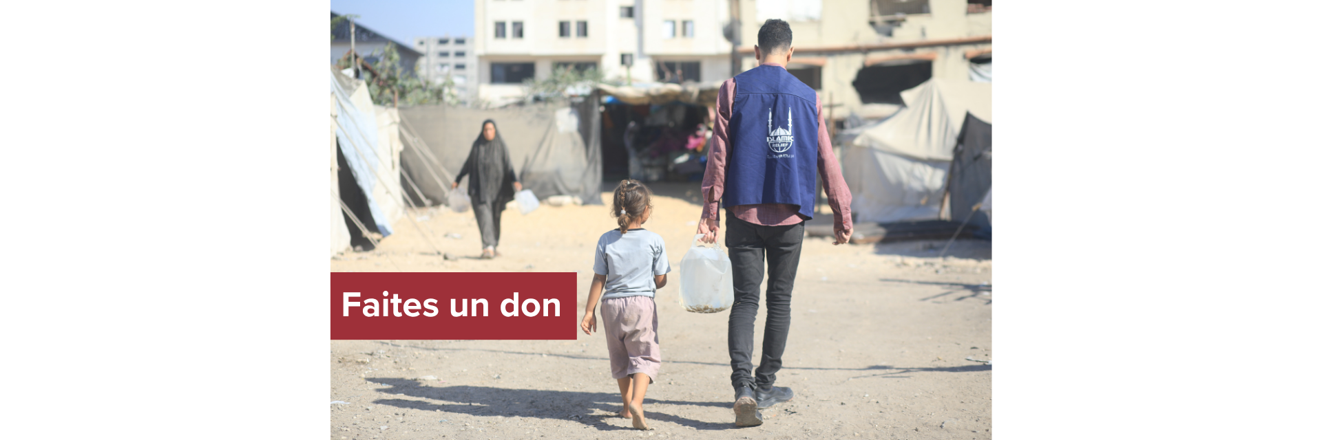 Un travailleur humanitaire transporte de l'eau pour un enfant dans un camp de déplacés.