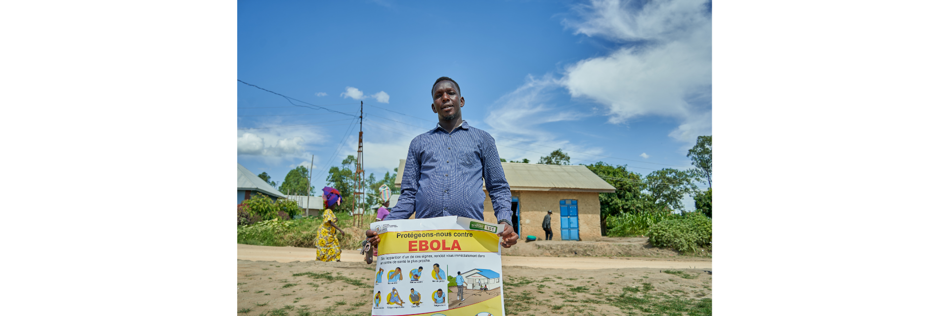 Un homme tenant une affiche sur laquelle il est écrit : « Protégeons-nous contre Ebola ».