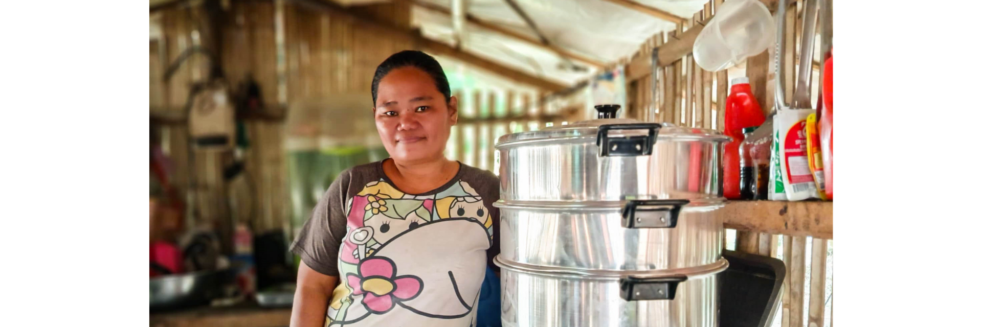 Une femme se tient dans une cuisine, à côté d'un ensemble de grands paniers à vapeur posés sur la cuisinière.