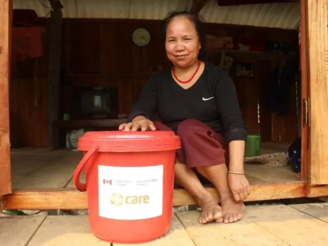 Une femme assise avec un seau de produits d'hygiène