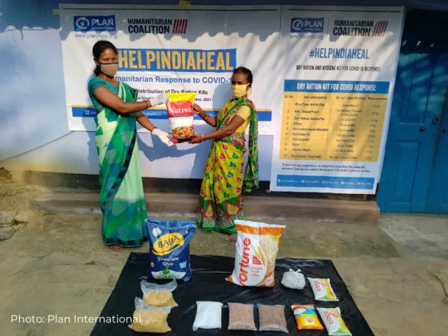 Deux femmes présentent le sac de nourriture offert aux survivants de la COVID-19 en Inde