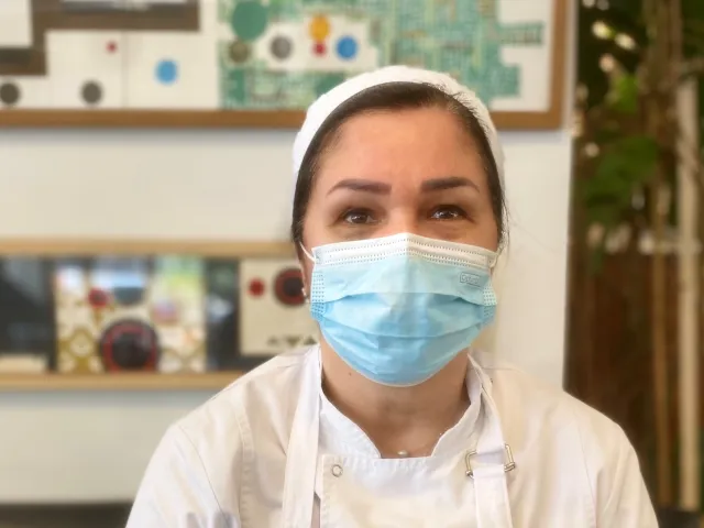 Une femme avec un masque et un tablier regarde en avant