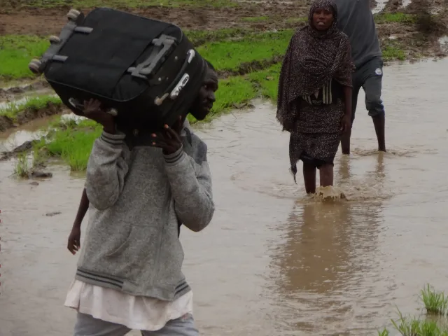 Un homme marche dans l'eau avec sa valise