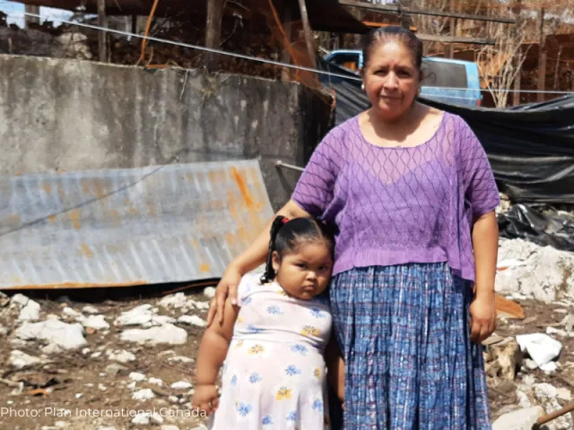 Geovana avec sa fille devant leur maison en ruines