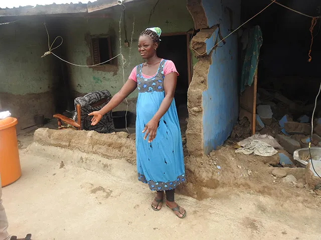 Une femme devant sa maison les bras étendus