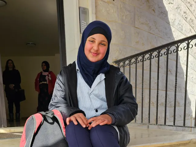 Lana sur les marches du centre éducatif, avec sa mère Fatouma debout derrière elle.