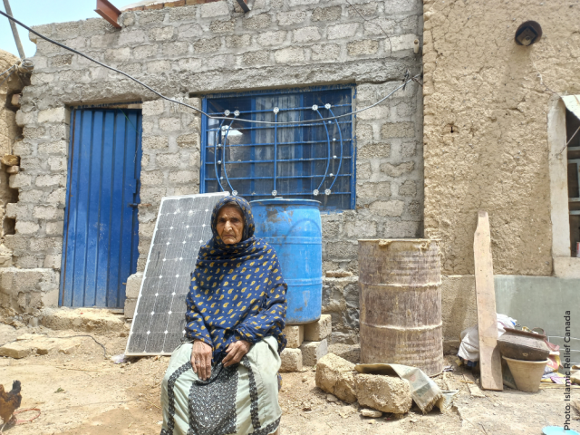Woman in Pakistan next to her restored house