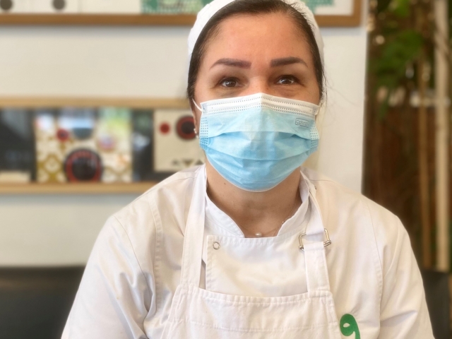 Une femme avec un masque et un tablier regarde en avant