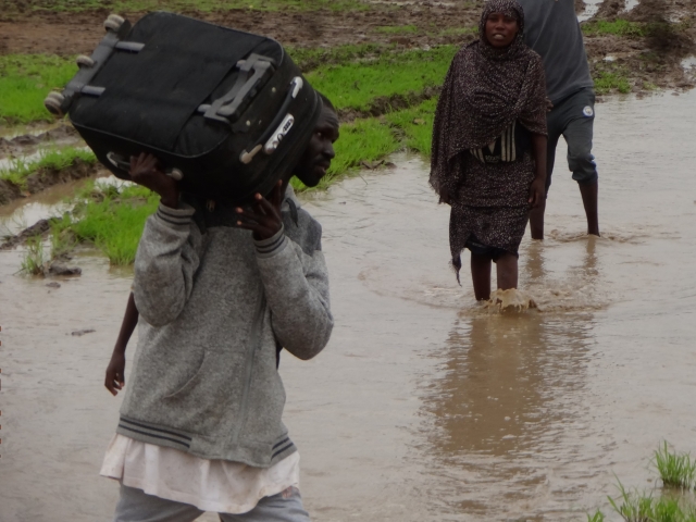 Un homme marche dans l'eau avec sa valise