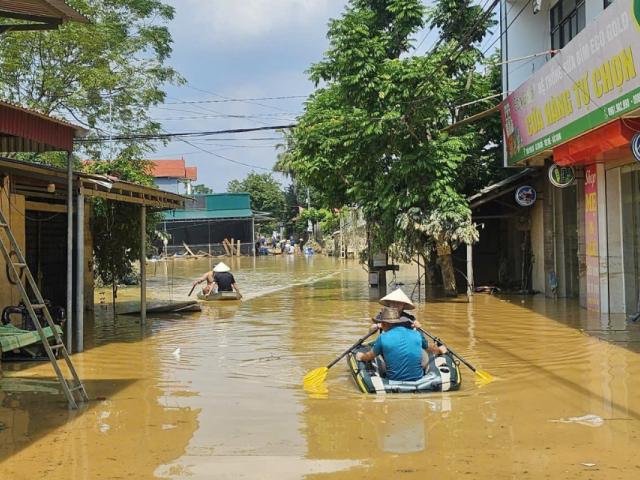 Des personnes à bord de bateaux pneumatiques pagayent dans une rue inondée au Vietnam.