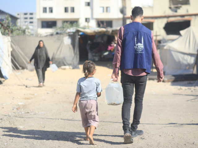 Un travailleur humanitaire apporte de l'eau à un enfant dans un camp de personnes déplacées